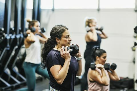 Frau macht Hantelkniebeugen während des Fitnesskurses im Fitnessstudio