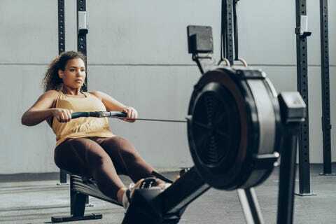 junge frau, die im fitnessstudio mit rudergerät trainiert