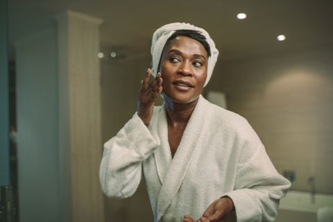 Frauen setzen auf Feuchtigkeitscreme auf ihrem Gesicht Haut